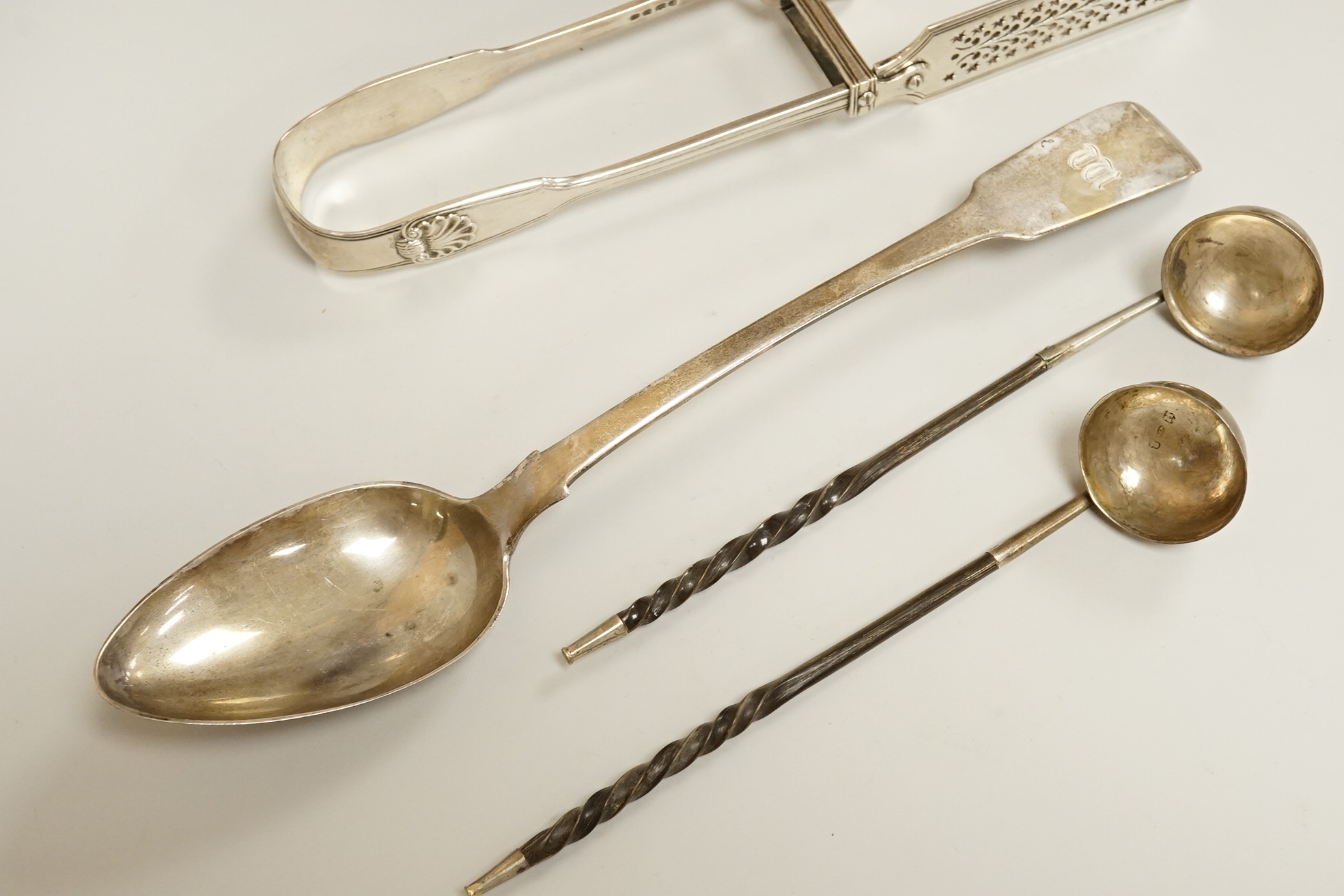 A pair of William IV silver fiddle, thread and shall pattern asparagus servers, a George IV silver fiddle pattern basting spoon, Robert Gainsford, Sheffield, 1826, 31.2cm, 10.8oz and two 19th century white metal toddy la